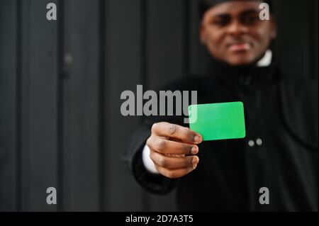 Uomo africano indossare durag nero tenere la bandiera libica a mano isolato sfondo scuro. Foto Stock