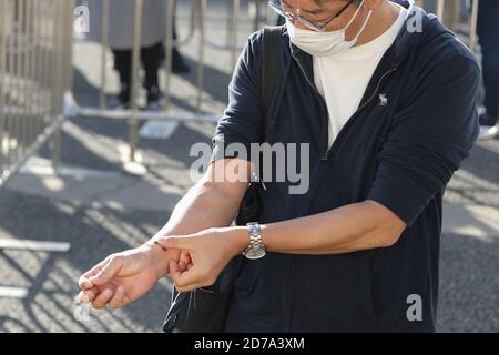 Tokyo. 21 Ott 2020. Un uomo che svolge il ruolo di spettatore ha messo un adesivo speciale che cambia i suoi colori in diverse condizioni di temperatura sul polso come misurazione della temperatura durante il test di dimostrazione di screening a Tokyo Big Sight a Tokyo, Giappone, 21 ottobre 2020. Credit: Xinhua/Alamy Live News Foto Stock