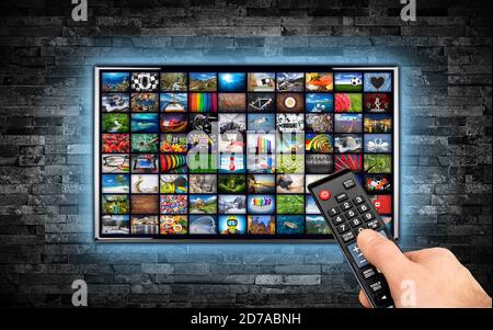 Schermo tv nero a schermo piatto con sfondo galleria di immagini. Televisore a parete montato su una parete di pietra ardesia scura che illumina lo sfondo blu LED. Più Foto Stock