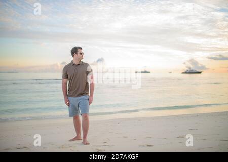 Mann stehend am Strand im Sonnenuntergang auf den Malediven Foto Stock