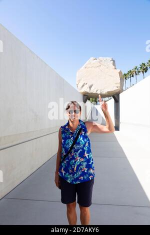 Il turista femminile si pone con l'installazione di arte di massi di massa Levitated al LACMA, Los Angeles, California, Stati Uniti d'America, Stati Uniti d'America Foto Stock
