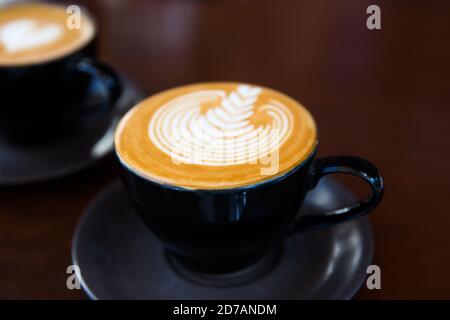 Due tazze di cappuccino caldo sullo sfondo della scrivania in legno. Ora della colazione. Vista dall'alto. Chiuso Foto Stock
