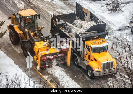 Spazzaneve sgombero lavoratori urbani che guidano camion che puliscono strade che rimuovono neve con spazzaneve attrezzature per servizi pesanti camion. Urbano invernale Foto Stock