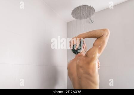 Doccia di lusso con doccia in bagno dell'hotel che si lava via la toscia dai capelli e dal corpo, vista posteriore dal retro. Stile di vita di bellezza maschile per la cura della pelle Foto Stock