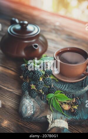 Tè alla frutta in una tazza con more. Il tè è composto da bacche e foglie di lamponi neri Foto Stock