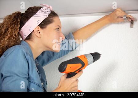 giovane handywoman che fora sul soffitto Foto Stock