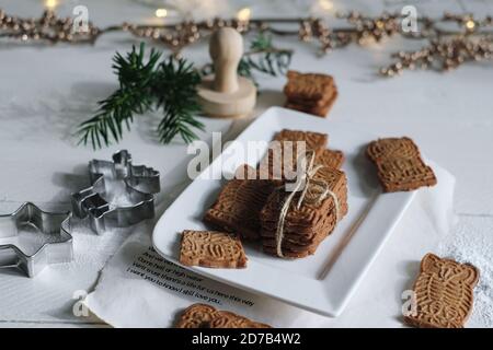 Umore di Natale, speculoos accatastato con speculoos legato con un nastro di imballaggio, splendidamente decorato su un piatto di porcellana bianca su un tavolo di legno bianco, io Foto Stock