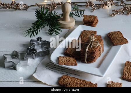 Umore di Natale, speculoos accatastato con speculoos legato con un nastro di imballaggio, splendidamente decorato su un piatto di porcellana bianca su un tavolo di legno bianco, io Foto Stock