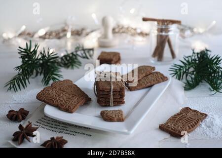 Umore di Natale, speculoos accatastato con speculoos legato con un nastro di imballaggio, splendidamente decorato su un piatto di porcellana bianca su un tavolo di legno bianco, io Foto Stock