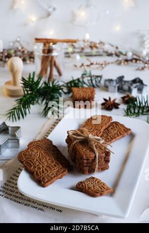 Umore di Natale, speculoos accatastato con speculoos legato con un nastro di imballaggio, splendidamente decorato su un piatto di porcellana bianca su un tavolo di legno bianco, io Foto Stock