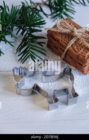 Avvento e umore di Natale, speculoos accatastati con un nastro di imballaggio legato, splendidamente decorato su un tavolo di legno bianco con zucchero in polvere e un biscotto Foto Stock