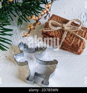 Avvento e umore di Natale, speculoos accatastati con un nastro di imballaggio legato, splendidamente decorato su un tavolo di legno bianco con zucchero in polvere e un biscotto Foto Stock