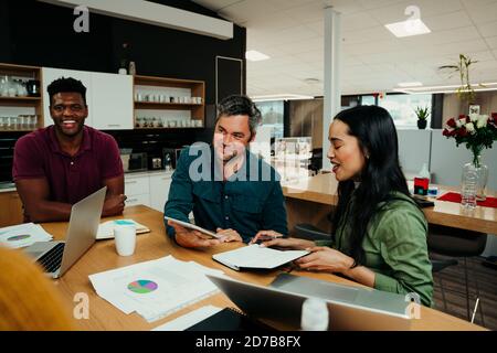 I partner si sono riuniti ridendo con il bonding discutendo il lavoro per il settimana prima della presentazione di fronte al capo e ai colleghi Foto Stock