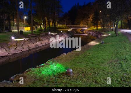 Helsinki/Finlandia - 12 MAGGIO 2019: Un bellissimo paesaggio notturno di un parco pubblico con un canale paesaggistico e un ponte pedonale. Foto Stock