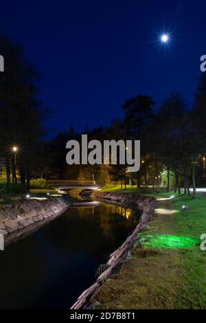 Helsinki/Finlandia - 12 MAGGIO 2019: Un bellissimo paesaggio notturno di un parco pubblico con un canale paesaggistico e un ponte pedonale. Foto Stock