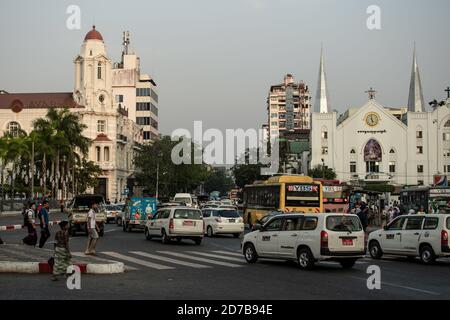 Yangon, Myanmar - 30 dicembre 2019: Traffico con i mezzi pubblici autobus, auto e pedoni vicino a Sule Pagoda nel centro della città Foto Stock