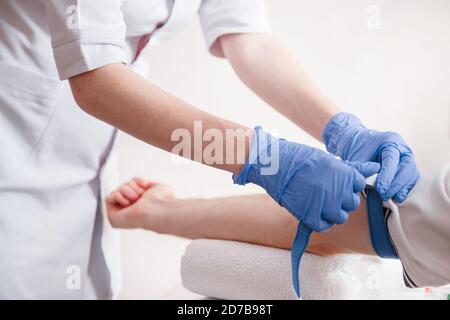 Infermiere digiuna il laccio medico sul braccio prima di prendere il sangue test Foto Stock