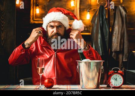 Brutale maschile sopportato Babbo Natale con orologio e champagne sempre resdy per incontrare Capodanno. Splendido sfondo e luci decorate a Natale Foto Stock