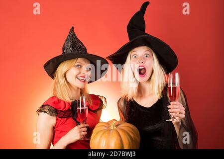 Due ragazze felici di giovane donna in costumi halloween delle streghe su festa su sfondo arancione. Foto Stock