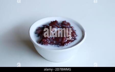 Porridge di riso glutinoso nero o hitam di bubur ketan con latte di cocco. Dolce indonesiano. Foto Stock