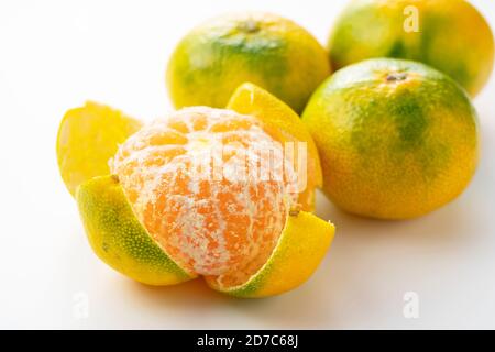 Arance di primo mandarino giapponesi sbucciate su sfondo bianco Foto Stock