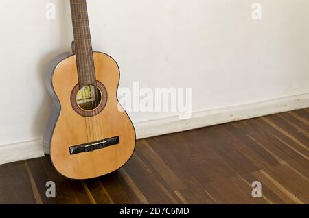 Ripresa ad alto angolo di chitarra acustica contro una parete bianca Foto Stock