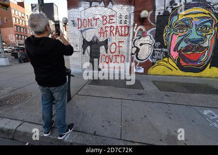 New York City, Stati Uniti. 21 Ott 2020. Un uomo usa uno smartphone per fotografare un murale su Houston Street che raffigura il presidente degli Stati Uniti Donald Trump come il triste reaper come i casi COVID-19 continuano ad aumentare negli Stati Uniti, New York, NY, 21 ottobre 2020. Il murale è stato dipinto da un artista che prende il nome di "Genius reale", le parole "non avere paura di Covid" sono state pronunciate dal presidente Trump durante la ripresa dal COVID-19. (Anthony Behar/Sipa USA) Credit: Sipa USA/Alamy Live News Foto Stock