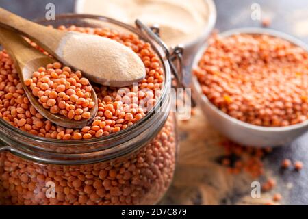 Lenticchie rosse e farina di lenticchie nei cucchiai di legno sopra la ciotola di lenticchie rosse. Foto Stock