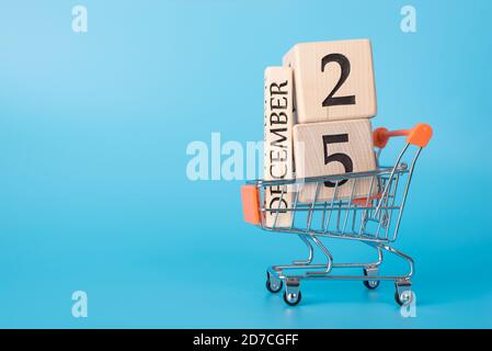 Offerta promozionale di Natale. Profilo laterale primo piano foto del carrello porta cubi con data 25 dicembre isolato su sfondo blu Foto Stock