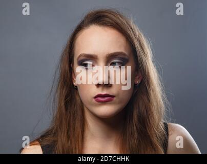 Foto di guardare la ragazza laterale con le labbra viola sfondo grigio Foto Stock