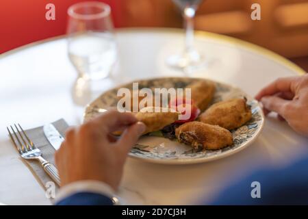 Primo piano di un uomo che mangia filetti di pollo fritti croccanti un ristorante Foto Stock