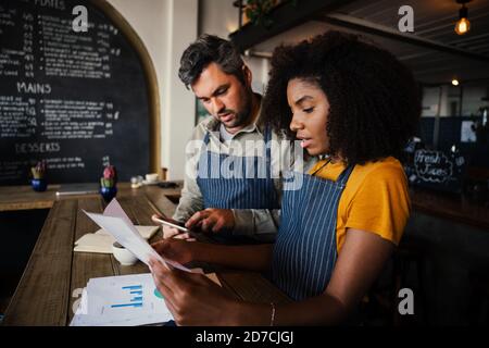 Collaboratori occupati che ordinano i conti bancari per la settimana lavorare in una caffetteria alla moda Foto Stock