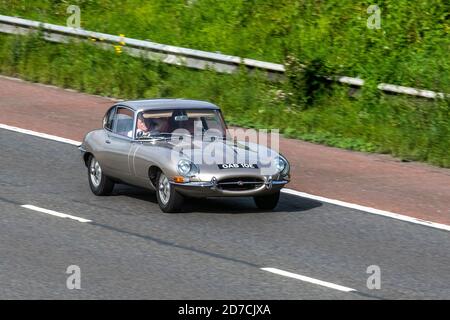 1967 60s Sessanta Gold Jaguar 2+2 e Type; traffico veicolare, veicoli in movimento, automobili, veicoli che guidano su strade del Regno Unito, 60s motori, automobilismo sulla rete stradale dell'autostrada M6 del Regno Unito Foto Stock