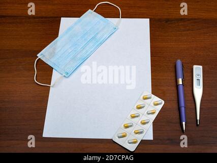 Pillole e termometro medico per maschera di influenza sulla carta vuota primo piano Foto Stock