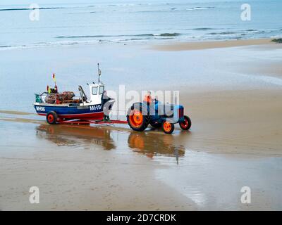Granchio o aragosta, pescatore che guida un trattore che trasporta la loro barca fuori dal mare Redcar Cleveland UK Foto Stock