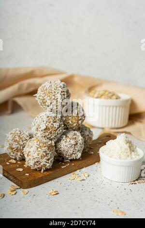 palle energetiche, fiocchi di avena interi e polvere di cocco, dolci a basso contenuto calorico, su sfondo chiaro Foto Stock