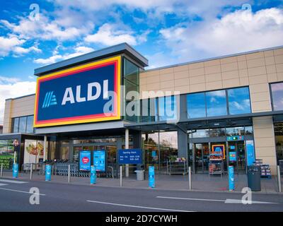 Il frontage e il logo del marchio di una filiale del rivenditore tedesco di sconti Aldi, portato in un parco locale di vendita al dettaglio a Wirral, Regno Unito, in un pomeriggio di sole Foto Stock