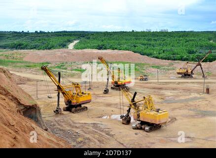 Enormi escavatori con pala elettrica in cava. I grandi dumper da miniera trasportano i minerali nelle miniere a cielo aperto di calcare. Dolomite più grande Foto Stock