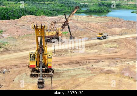 Enormi escavatori con pala elettrica in cava. I grandi dumper da miniera trasportano i minerali nelle miniere a cielo aperto di calcare. Dolomite più grande Foto Stock