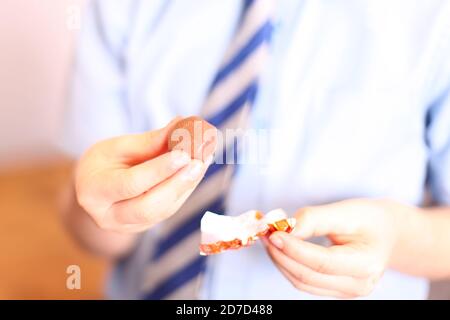 Bambino che disimballa Quality Street Orange Crunch cioccolato dolce, primo piano Foto Stock