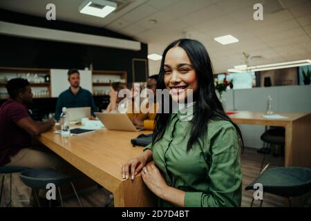 Bella donna d'affari indiana sorridente rilassante nel foyer mentre colleghi preparatevi alla riunione Foto Stock