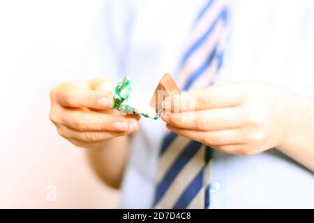 Bambino che disimballa il cioccolato di qualità di strada Verde Triangolo dolce, primo piano Foto Stock