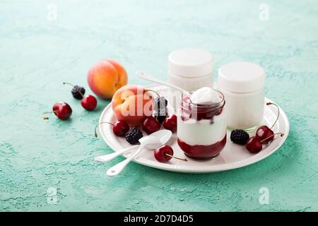 Yogurt di cocco fatto in casa in vasi di vetro con frutti di bosco e frutta freschi, fuoco selettivo Foto Stock