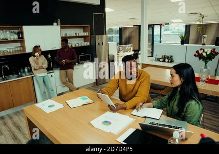 Donna di affari indiana e maschio di razza mista che discutono le idee per ricerca di nuovi progetti su notebook e tablet digitali atrio dell'ufficio Foto Stock