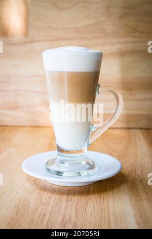 un caffè latte servito in un bicchiere trasparente con legno sfondo Foto Stock