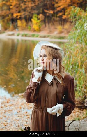 Ritratto di giovane donna in abito retrò sorridente vicino al lago in autunno Foto Stock