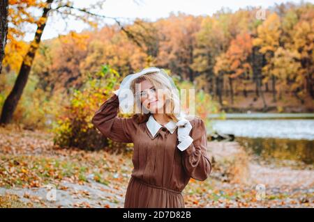 Ritratto di giovane donna in abito retrò sorridente vicino al lago in autunno Foto Stock