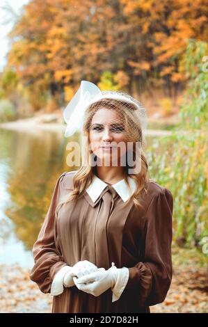 Ritratto di giovane donna in abito retrò sorridente vicino al lago in autunno Foto Stock