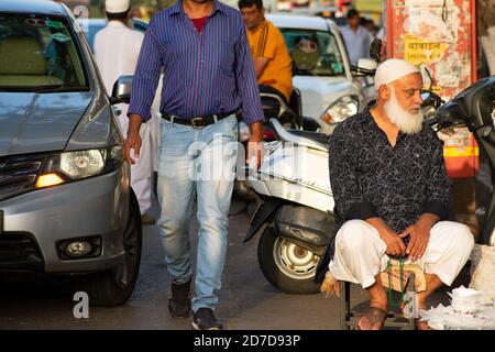 Mumbai, India - 22 marzo 2019: Vecchio musulmano sconosciuto seduto su una piccola sedia sul lato della strada a collina, Bandra a Mumbai. Foto Stock