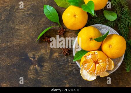 Frutta invernale. Freschi e succosi mandarini clementini con foglie su rustico tavolo di legno. Vista dall'alto sfondo piatto. Spazio di copia. Foto Stock